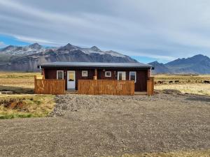 a house in the desert with mountains in the background at Aurora Cabins in Höfn