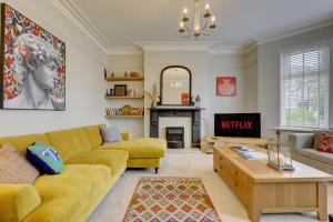 a living room with a yellow couch and a fireplace at Stylish 2 Bedroom Maisonette With Parking in Harrogate