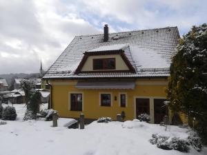 a yellow house with snow on the roof at apartmány Zak in Frymburk