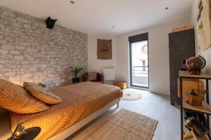 1 dormitorio con cama y pared de piedra en La Fabrique, Loft 100 m2, en Rives