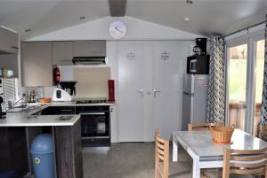 uma cozinha com armários brancos, uma mesa e um relógio em Spacieux Mobil-home N°502 - 2 chambres - dans Camping 4 * em Gastes