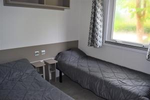 a room with two beds and a table and a window at Spacieux Mobil-home N°502 - 2 chambres - dans Camping 4 * in Gastes