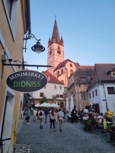 un grupo de personas caminando por una calle con una torre del reloj en Dioniss Apartment, en Sibiu
