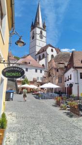 a person walking down a street with a clock tower at Dioniss Apartment in Sibiu