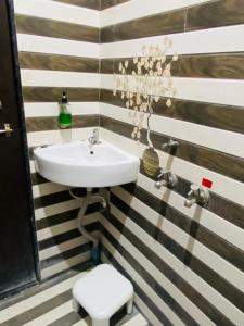 a bathroom with a sink on a striped wall at Hotel Meghmalhar Lodging in Jejūri
