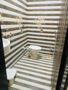 a bathroom with black and white striped walls and a toilet at Hotel Meghmalhar Lodging in Jejūri