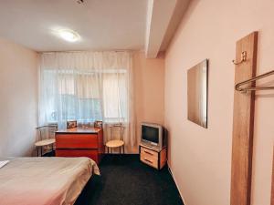 a bedroom with a bed and a desk and a tv at Guest House near Railway Station in Kyiv