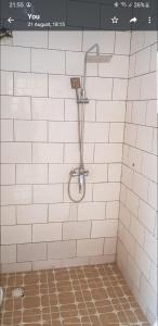 een witte betegelde douche met een douchekop aan de muur bij The bb's in Brusubi