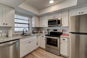 a kitchen with white cabinets and stainless steel appliances at Yellow Sunshine Oceanfront Townhouse, Private Balcony in Ponce Inlet
