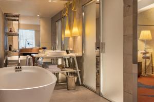 a bathroom with a bath tub and a table at Too Hotel Paris - MGallery in Paris