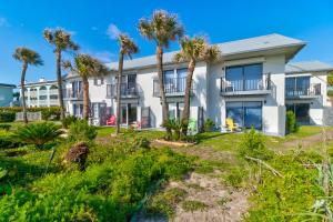 a large white building with palm trees in front of it at Blue Skies Oceanfront 2 bedroom townhouse in Ponce Inlet