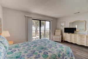 a bedroom with a bed and a television and a balcony at Dolphin Watcher 2 Bed Townhouse in Ponce Inlet