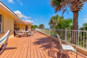 a wooden deck with chairs and a table and palm trees at Beachfront 4 Bedroom 4 Bath with Huge Deck Wifi in Daytona Beach