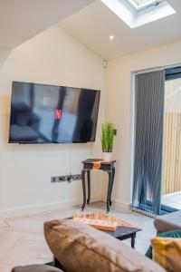 een woonkamer met een bank en een tv aan de muur bij BV Comfy Spacious 3 Bedroom TownHouse At One Cliff Oak Leeds Perfect For Contractors in Leeds