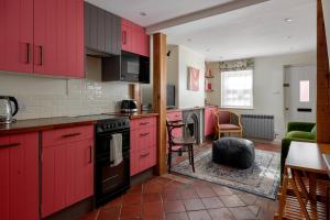 a kitchen with red cabinets and a living room at Pearls Cottage in Farnham