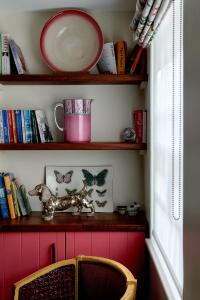 um quarto com uma prateleira com livros e uma cadeira em Pearls Cottage em Farnham