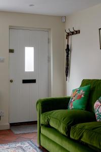 a green couch in a living room with a door at Pearls Cottage in Farnham