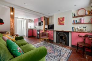 sala de estar con sofá verde y chimenea en Pearls Cottage en Farnham