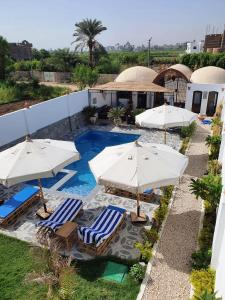 a swimming pool with two umbrellas and chairs and a pool at CASA LOKO Guest House in Luxor