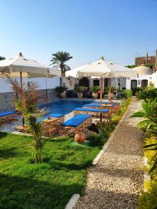 een zwembad met parasols en een resort bij CASA LOKO Guest House in Luxor