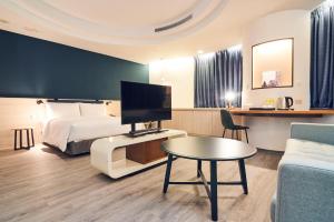 台北的住宿－雀客藏居台北南港，一间酒店客房,配有一张床、一台电视和一张桌子