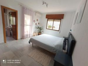 a bedroom with a bed and a bathroom with a window at House in a cove Almunecar in Almuñécar