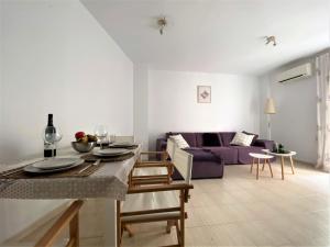 sala de estar con mesa y sofá púrpura en Apartamento Felipe Neri 10, en Málaga