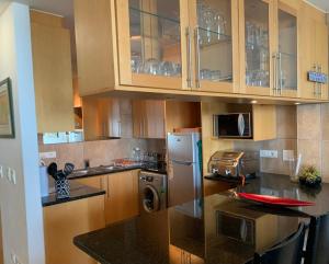 a kitchen with wooden cabinets and a refrigerator at Beachfront Gem / Free Parking / A/C in Cape Town