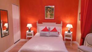 a bedroom with orange walls and a bed with red pillows at Hotel Relais Du Postillon in Antibes