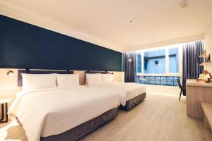 a hotel room with two beds and a large window at CHECK inn Select Taipei Nangang in Taipei