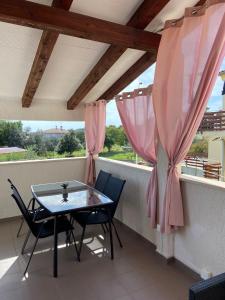 d'une table et de chaises sur un balcon avec des rideaux roses dans l'établissement Apartment MADIS & Free Bikes, à Pula