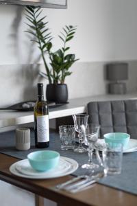 una bottiglia di vino seduta su un tavolo con piatti e bicchieri di Apartament 4 pory roku a Kudowa-Zdrój