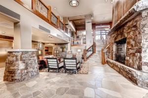 - un hall avec une grande cheminée en pierre et des chaises dans l'établissement Luxury 3 Bedroom Ski In, Ski Out One Ski Hill Residence Located At The Base Of Peak 8 With Hot Tub Access, à Breckenridge