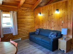 a living room with a blue couch and a table at Adventures East Cottages and Campground in Baddeck Inlet