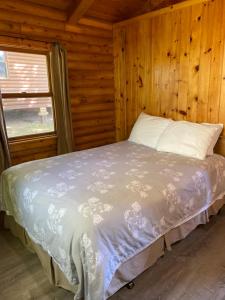 1 dormitorio con 1 cama en una cabaña de madera en Adventures East Cottages and Campground, en Baddeck Inlet