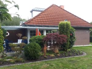 a house with a garden and bushes at Bungalow 6091 in Tossens in Butjadingen OT Tossens