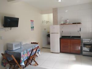 uma cozinha com uma mesa e um frigorífico branco em Quitinetes Canto Verde Caraguá em Caraguatatuba