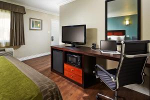 a hotel room with a bed and a desk with a television at American Inn Downey in Downey