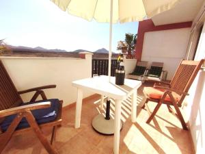 una mesa blanca y sillas con sombrilla en el balcón en Sunset House et piscine, en Parque Holandes