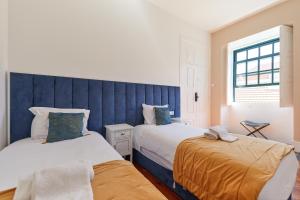 a bedroom with two beds and a blue headboard at A Portuguesa Guest House in Porto