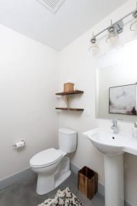 a white bathroom with a toilet and a sink at Brewery District 2-Story 2BR Apt Near Fiserv with Rooftop, Gym, and Parking in Milwaukee