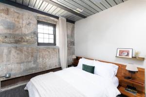 a bedroom with a white bed and a stone wall at Brewery District 2-Story 2BR Apt Near Fiserv with Rooftop, Gym, and Parking in Milwaukee