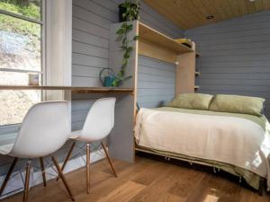 ein Schlafzimmer mit zwei weißen Stühlen und einem Bett in der Unterkunft Golden Tiny Homes in Golden