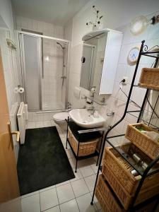 ein weißes Bad mit einem Waschbecken und einer Dusche in der Unterkunft Ferienwohnung Rostock Nähe Warnemünde in Rostock
