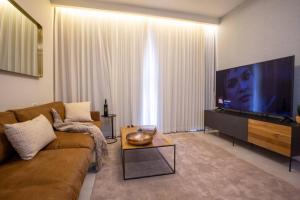 a living room with a couch and a flat screen tv at Aphrodite Suite in Ashkelon