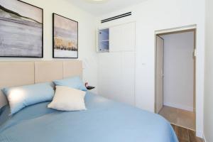 Un dormitorio con una cama azul y algunas fotos en la pared en Aphrodite Suite en Ashqelon