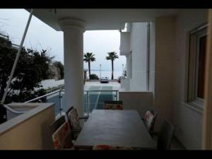 a table and chairs on a balcony with a view of the ocean at Beachfront Sion Sarande Apartment 1 in Sarandë