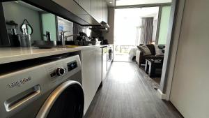 uma cozinha com uma máquina de lavar roupa num quarto em Modern Luxury Studio with Breathtaking City Views - No Load Shedding na Cidade do Cabo