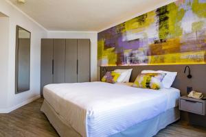 a bedroom with a large white bed with a painting on the wall at Palladium Business Hotel in Montevideo