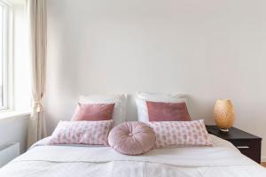 a bedroom with a bed with pink pillows at Penthouse with amazing views of Copenhagen! in Copenhagen